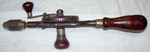 An old hand drill or "eggbeater" drill. Note the hollow wooden handle, with screw-on cap, used to store drill bits.