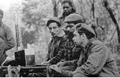 Listening to a Zenith Trans-Oceanic shortwave receiver are (seated from the left) Rogelio Oliva, Jos&eacute; Mar&iacute;a Mart&iacute;nez Tamayo (known as "Mbili" in the Congo and "Ricardo" in Bolivia), and Guevara. Standing behind them is Roberto S&aacute;nchez ("Lawton" in Cuba and "Changa" in the Congo).